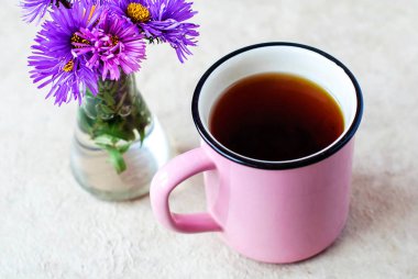 Siyah çay hafif bir arka plan ve mor çiçekler pembe bir fincan.