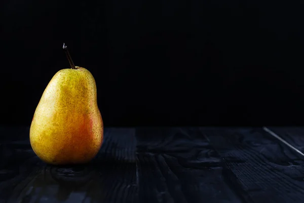Siyah bir arka plan ve ahşap bir masa üzerinde sarı armut — Stok fotoğraf