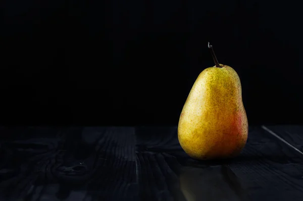 Siyah bir arka plan ve ahşap bir masa üzerinde sarı armut — Stok fotoğraf