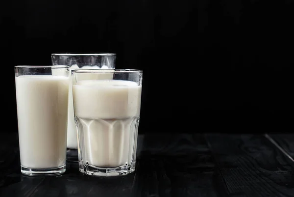 Bara tre glas mjölk på en svart bakgrund — Stockfoto