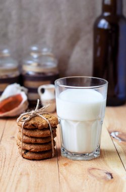 Kuru üzüm ve bir bardak süt ahşap bir masa üzerinde yararlı kahvaltı yulaf ezmeli kurabiye.