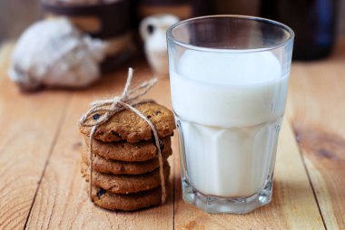 Kuru üzüm ve bir bardak süt ahşap bir masa üzerinde yararlı kahvaltı yulaf ezmeli kurabiye.