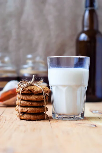 Colazione utile biscotti di farina d'avena con uva passa e un bicchiere di latte su un tavolo di legno . — Foto Stock