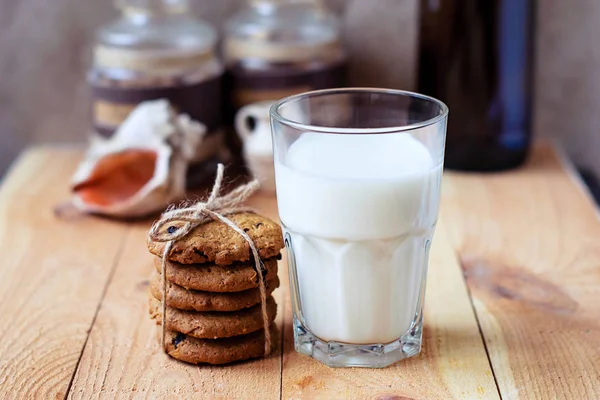 Kuru üzüm ve bir bardak süt ahşap bir masa üzerinde yararlı kahvaltı yulaf ezmeli kurabiye.