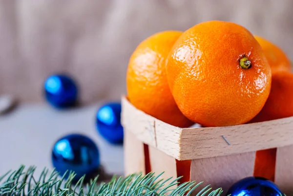 Mandarins in a wooden box with Christmas toys and a garland — Stock Photo, Image