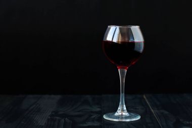 Siyah arka planda bir kadeh kırmızı şarap.
