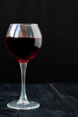 Siyah arka planda bir kadeh kırmızı şarap.