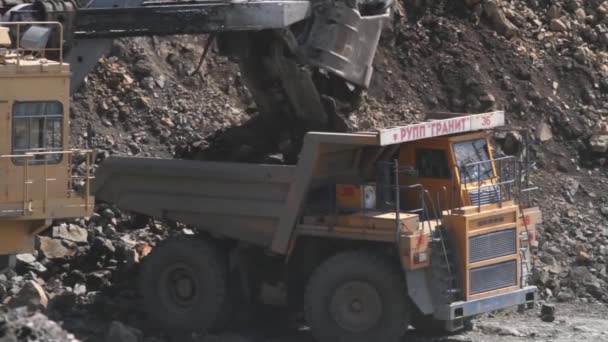 Vitryssland, Mikhashevichy: juni 2016: grävmaskin laddar en sten i den tunga lastbilen Belaz i stenbrottet gruvdrift granit — Stockvideo