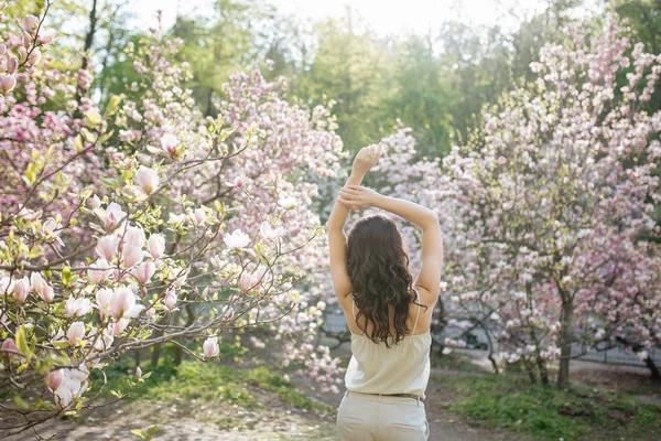 Beauty woman standing on Magnolia blossoming flowers background. — Stock Photo, Image