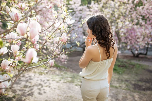 Beauty woman standing on Magnolia blossoming flowers background. — Stock Photo, Image