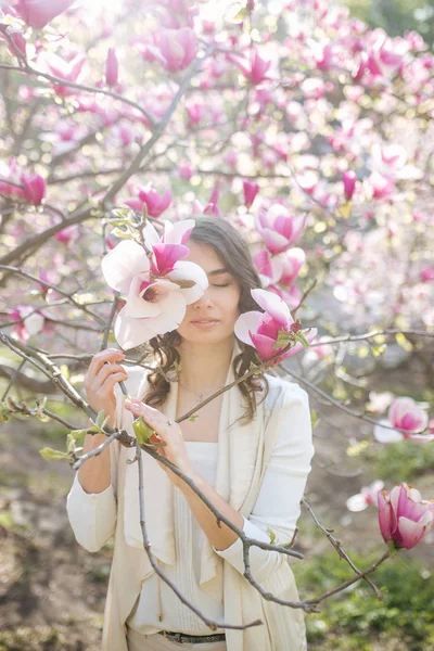 Beauty woman standing on Magnolia blossoming flowers background. — Stock Photo, Image