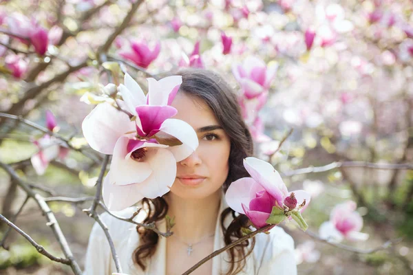 Beauty woman standing on Magnolia blossoming flowers background. — Stock Photo, Image