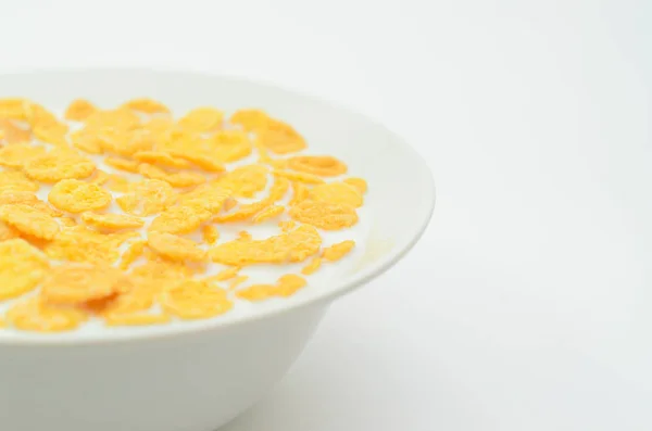 Fiocchi di mais con latte su un cucchiaio in una ciotola su uno sfondo leggero . — Foto Stock