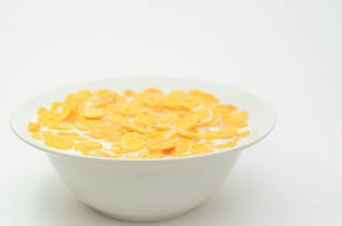 Bir kaşık hafif bir arka plan üzerinde bir kasede süt ile Mısır gevreği.