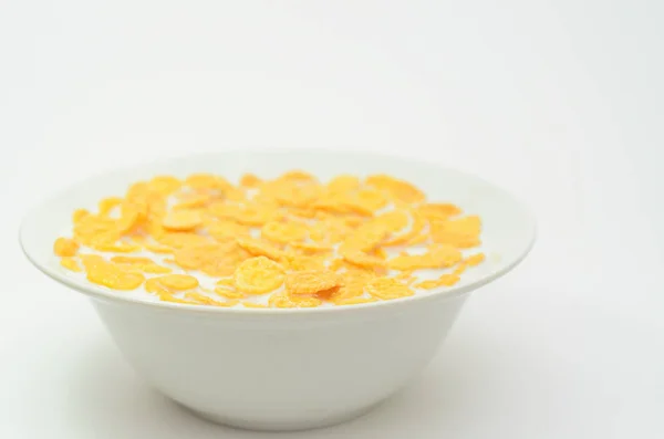 Cornflakes with milk on a spoon in a bowl on a light background. — Stock Photo, Image