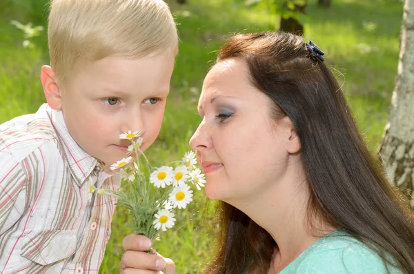 The boy gives flowers to his mother.
