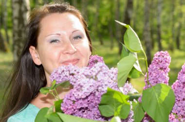 Bir buket çiçek parkta gülümseyen mutlu kadınla.