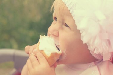 Küçük bir kız dondurma yiyor ve onun yüzüne bulaşmış.