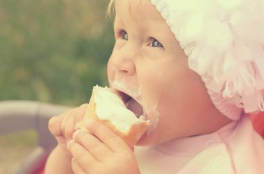 Küçük bir kız dondurma yiyor ve onun yüzüne bulaşmış.