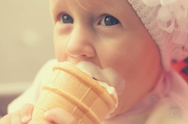 Küçük bir kız dondurma yiyor ve onun yüzüne bulaşmış.