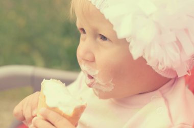 Küçük bir kız dondurma yiyor ve onun yüzüne bulaşmış.