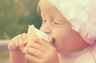 Küçük bir kız dondurma yiyor ve onun yüzüne bulaşmış.