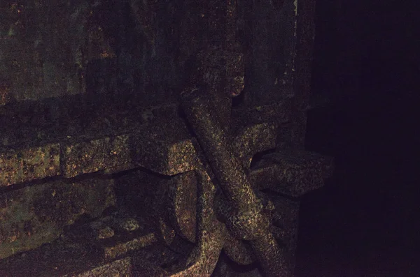 Old terrible rusty door from the bomb shelter in a completely dark dungeon.