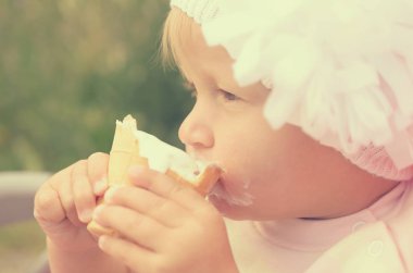 Küçük bir kız dondurma yiyor ve onun yüzüne bulaşmış.