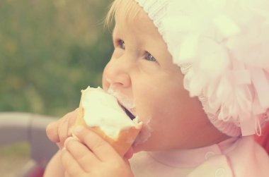 Küçük bir kız dondurma yiyor ve onun yüzüne bulaşmış.