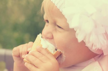 Küçük bir kız dondurma yiyor ve onun yüzüne bulaşmış.