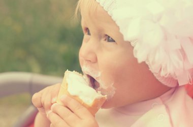 Küçük bir kız dondurma yiyor ve onun yüzüne bulaşmış.