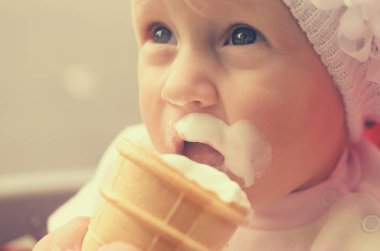 Küçük bir kız dondurma yiyor ve onun yüzüne bulaşmış.