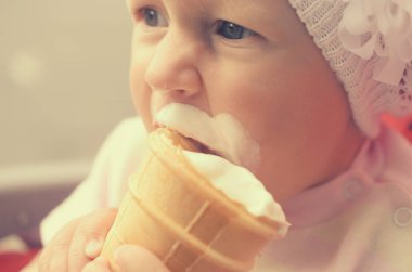 Küçük bir kız dondurma yiyor ve onun yüzüne bulaşmış.