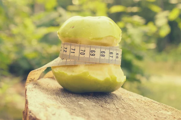 Una manzana verde con una cinta verde y una cinta métrica . — Foto de Stock