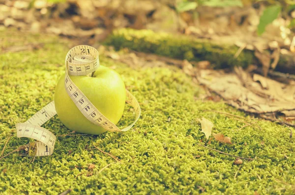 Manzana verde sobre hierba verde con cinta métrica y sin . — Foto de Stock
