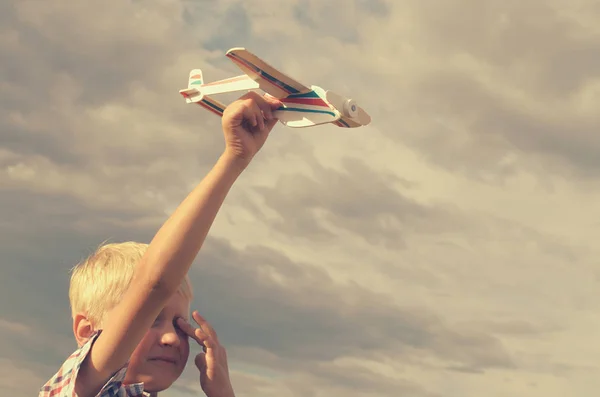 Der Junge lässt mit der Hand das Modell des Flugzeugs in den Himmel steigen. — Stockfoto