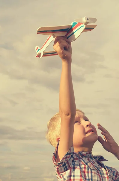 Der Junge lässt mit der Hand das Modell des Flugzeugs in den Himmel steigen. Stockbild