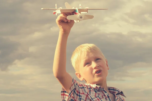 Der Junge lässt mit der Hand das Modell des Flugzeugs in den Himmel steigen. Stockfoto