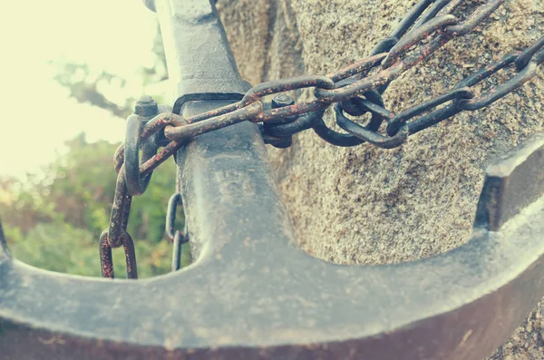 Uma estátua de uma grande âncora de metal, acorrentada a uma pedra . — Fotografia de Stock