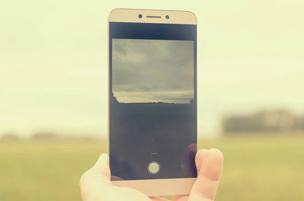 The phone\'s gadget in someone\'s hand takes a photo or video.