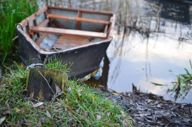 Nehir kıyısında bir demir zinciri tarafından demirlemiş harap bir tekne.