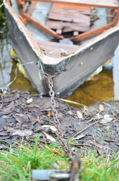 Un bateau délabré amarré au bord de la rivière par une chaîne de fer . — Photo