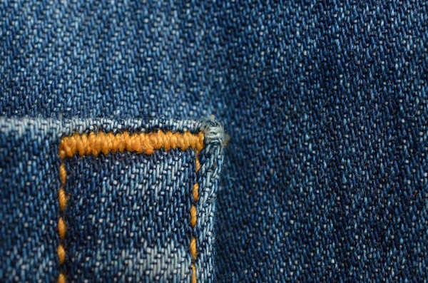 Textiel textuur van blue jeans met oranje stiksels. — Stockfoto