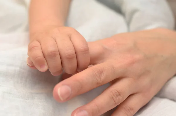 Рука ребенка держит маму за палец . — стоковое фото