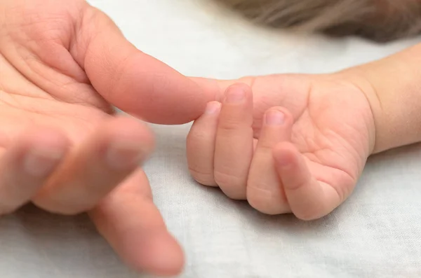 A child's hand holds Mom by the finger. — Stock Photo, Image