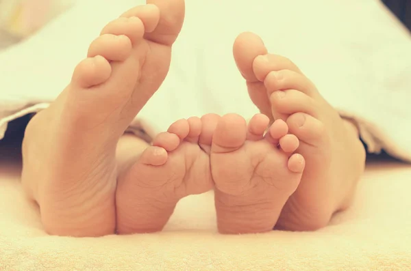 Детские ножки из-под одеяла на кровати . — стоковое фото
