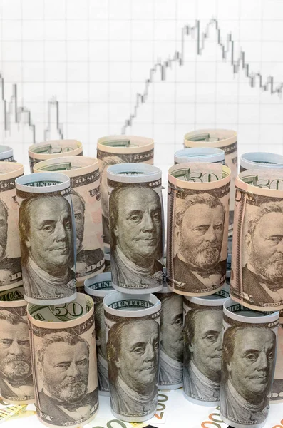 Mnoho zkroucené dolarové bankovky na pozadí finanční grafy. — Stock fotografie
