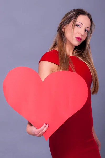 Mulher vestindo vestido vermelho segurando grande sinal de coração símbolo de amor — Fotografia de Stock