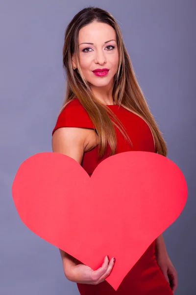 Mulher vestindo vestido vermelho segurando grande sinal de coração símbolo de amor — Fotografia de Stock