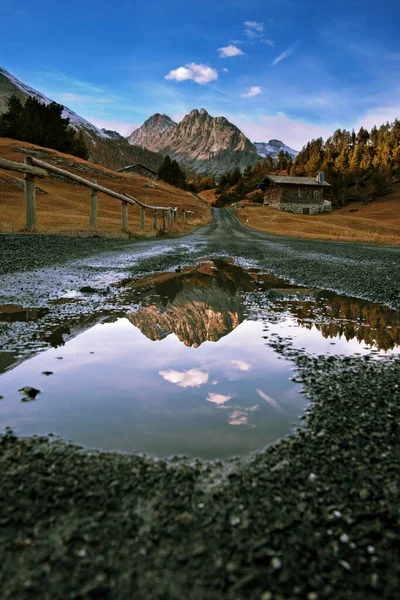 Mountain road. Reflection of mountains in a puddle — Stock Photo, Image